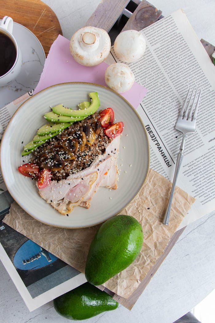 Top view of a balanced meal with turkey, avocado, mushrooms, and more on a plate.